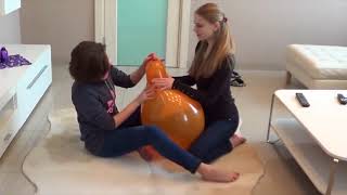 2 girls blow to pop big balloon
