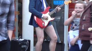 Man in shorts and high heels playing guitar in Liverpool city centre.