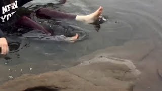 Girl plays with water dressed In the winter sea Trousers underwater feet white foot HD
