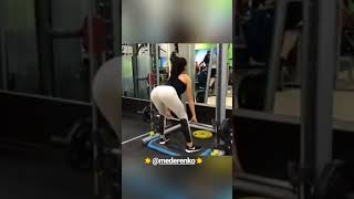Девушка приседает со штангой (вид сзади)