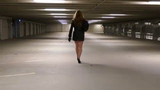 Crossdresser in garage wearing black high heels pumps and leather coat