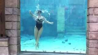 Female diver underwater performs cool tricks underwater