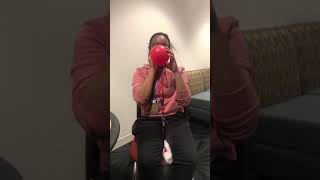 Brylonde blowing up a red balloon to pop enjoy