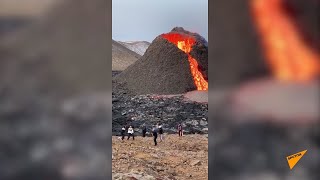 Люди играют в волейбол у подножия извергающегося вулкана