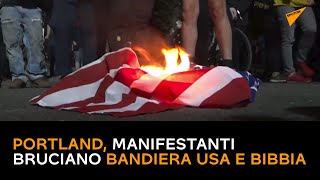 Portland, manifestanti bruciano bandiera USA e Bibbia