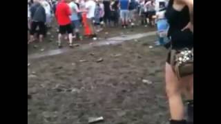 Guy at music festival slides underneath a girl taking a piss
