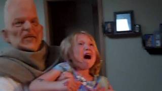 Dad scares daughter with a conehead mask.
