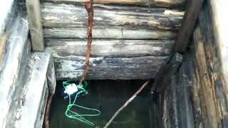 Grandmother collects spring water from a well