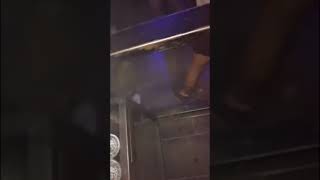 Drunk girl at the club pees in beer mug on dance floor