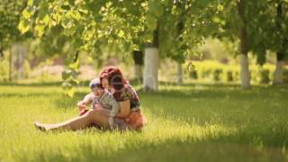 Happy smiling mother and son child sitting on grass and play in summer day