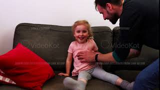 A father tickles his daughter. Little girl a laughs.
