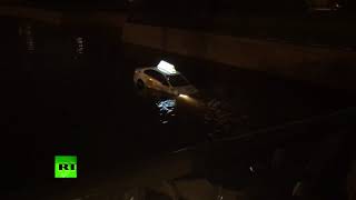 Автомобиль «Яндекс.Такси» с водителем и пассажиром внутри плывёт по каналу в центре Петербурга