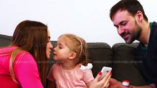 The family looks at the smartphone, the daughter kisses mom and dad