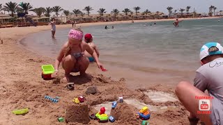 Девочки играют с машинками в песке на берегу моря